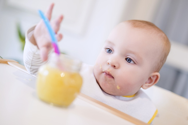 Um bebê agarrando um pote de comida
 - Foto, Imagem