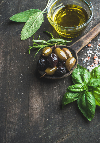 Green and black Mediterranean olives with fresh herbs - Foto, afbeelding