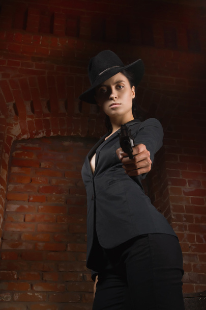 Γυναίκα στυλ φιλμ νουάρ σε ένα μαύρο κοστούμι με πυροβόλο όπλο - Φωτογραφία, εικόνα