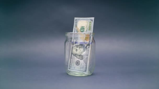 Mulher coloca o dólar americano 100 em um frasco de vidro
 - Filmagem, Vídeo