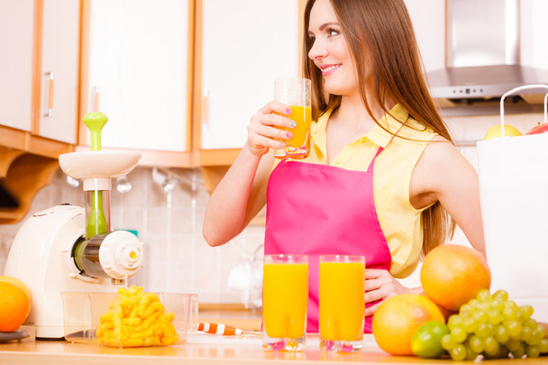 Woman in kitchen drinking fresh orange juice  - Foto, afbeelding