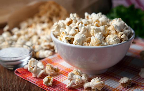 popcorn into a bowl on a napkin in the kitchen - Photo, Image