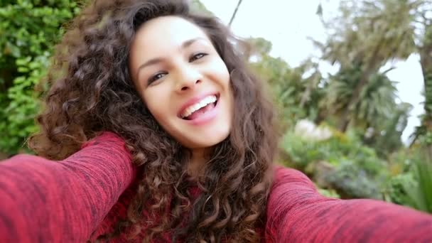 Retrato de mujer joven feliz con hermoso pelo rizado tomando selfie en el parque, cámara lenta
 - Imágenes, Vídeo