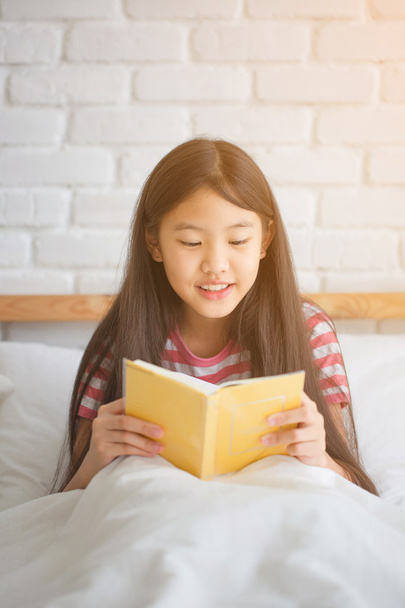 Asian girl reading story book on the bed - Photo, Image