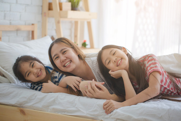Famille asiatique en bonne santé souriant et allongé sur le lit, Happy family
 - Photo, image