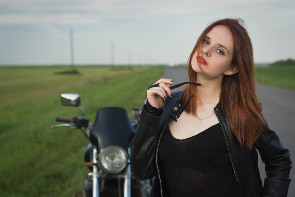 革のジャケットのバイクに近いポーズでバイク少女 - 写真・画像