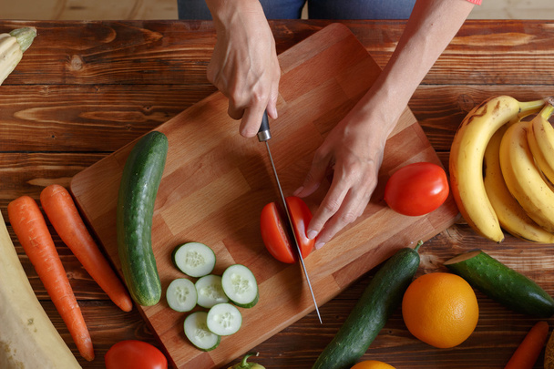 女性が夕食のトマトや他の野菜を切っています。 - 写真・画像