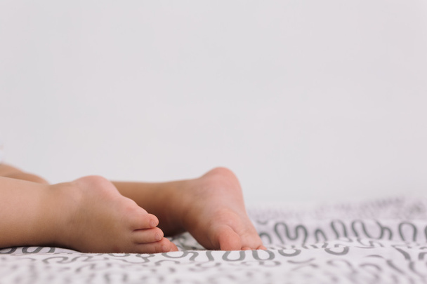 Barefoot baby on bedspread - Photo, image