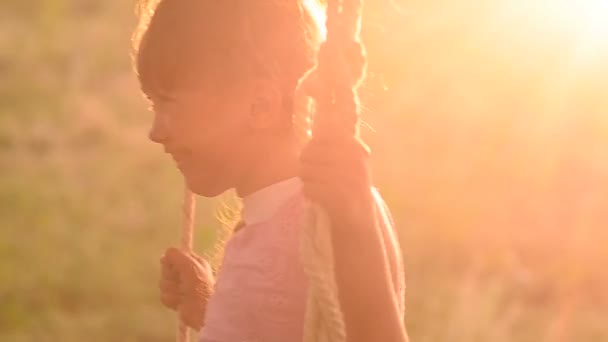Het meisje schudt op een schommel op een zonsondergang - Video