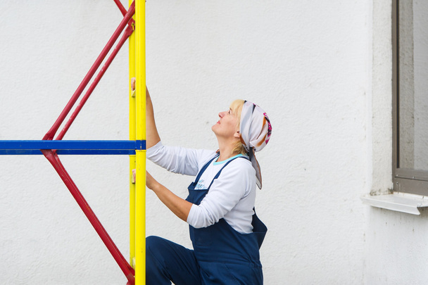 Femme en uniforme de constructeur monte sur une échelle de construction
. - Photo, image