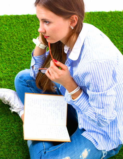 Жінка читає книгу сидить на зеленій траві
 - Фото, зображення