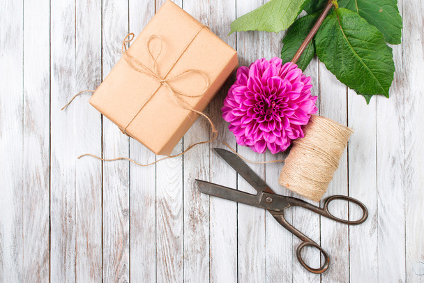 Handgemaakte doos van de gift en roze chrysant bloem op houten achtergrond. Concept van natuurlijke stijl ontwerp. - Foto, afbeelding