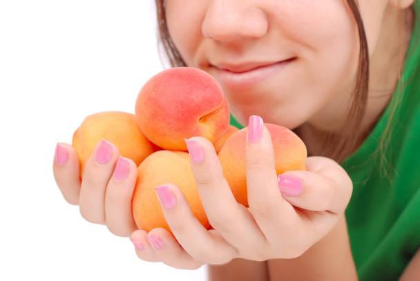 Руки женщины держат абрикосы у лица.
 - Фото, изображение