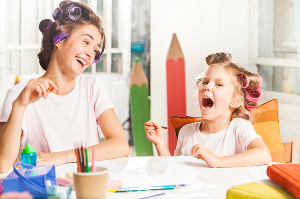 The young mother and her little daughter drawing with pencils at home - Foto, Imagen