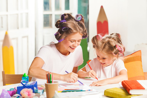 La joven madre y su hijita dibujando con lápices en casa
 - Foto, Imagen