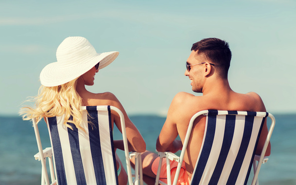 happy couple sunbathing in chairs on summer beach - Foto, Bild