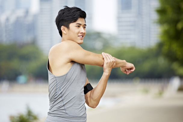 joven asiático hombre estiramiento brazos
 - Foto, imagen