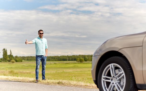 man hitchhiking and stopping car at countryside - Zdjęcie, obraz