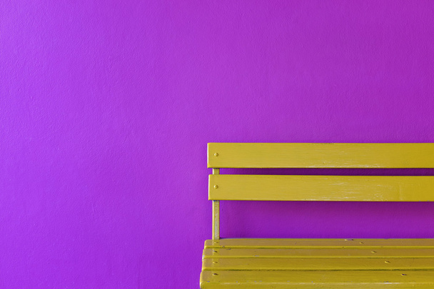 yellow wood bench on vivid violet wall background - Foto, Bild