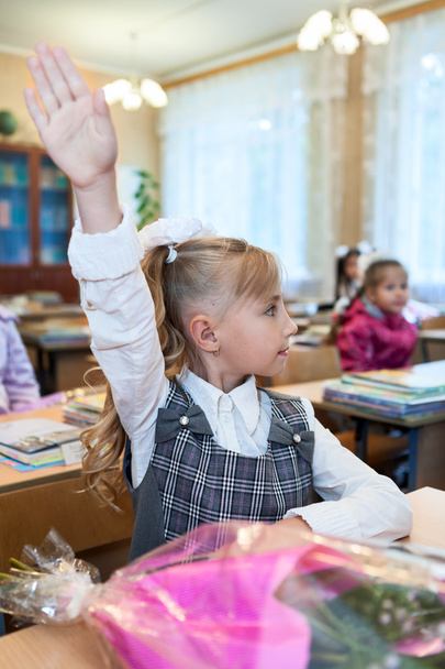 Kislány egy diák, aki felemeli a kezét válaszért az iskolában. - Fotó, kép