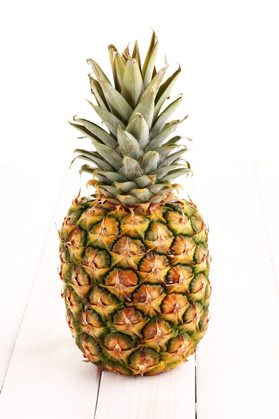 Pineapple on white wooden table - Foto, afbeelding