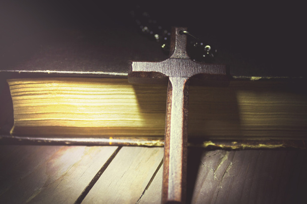 Kruis en boek op een houten tafel - Foto, afbeelding