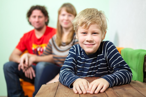 Happy smiling son sitting on foreground of his parent on the sofa - Fotoğraf, Görsel