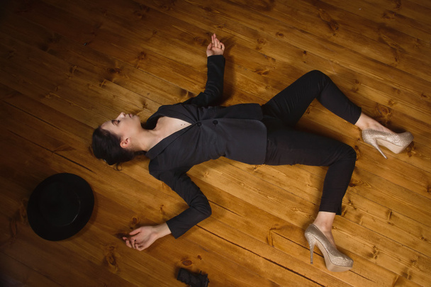 vrouw in een zwart pak met geweer liggend op de vloer - Foto, afbeelding