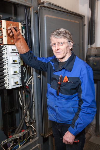 Electrician Caucasian repairman in blue uniform standing near high voltage industrial panel - Valokuva, kuva