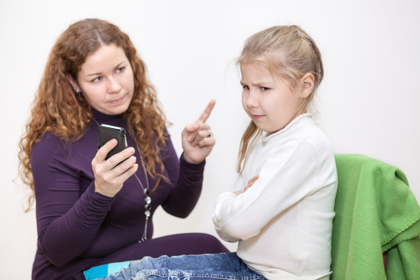 Mom scolding a child for viewing inappropriate content on your smartphone - Valokuva, kuva