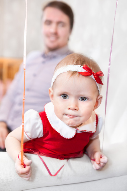 Caucasian baby girl looking at camera with father on background - Foto, Bild