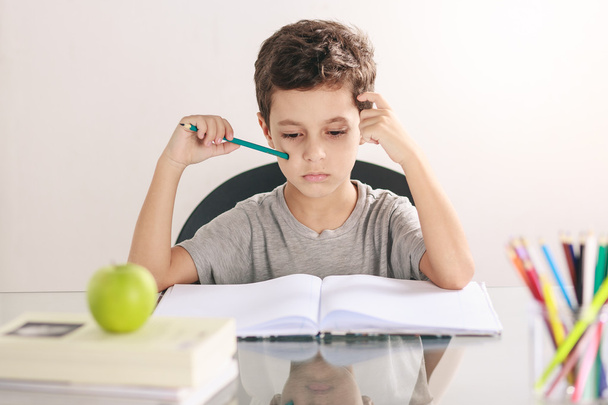 Candid portrait of a boy doing his homework and studying at home - Fotoğraf, Görsel