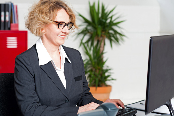 Aged woman in eyeglasses working on computer - Zdjęcie, obraz