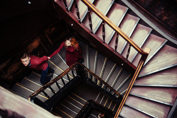 Пара молодих людей на дерев'яних сходах біля входу в старий будинок
 - Фото, зображення
