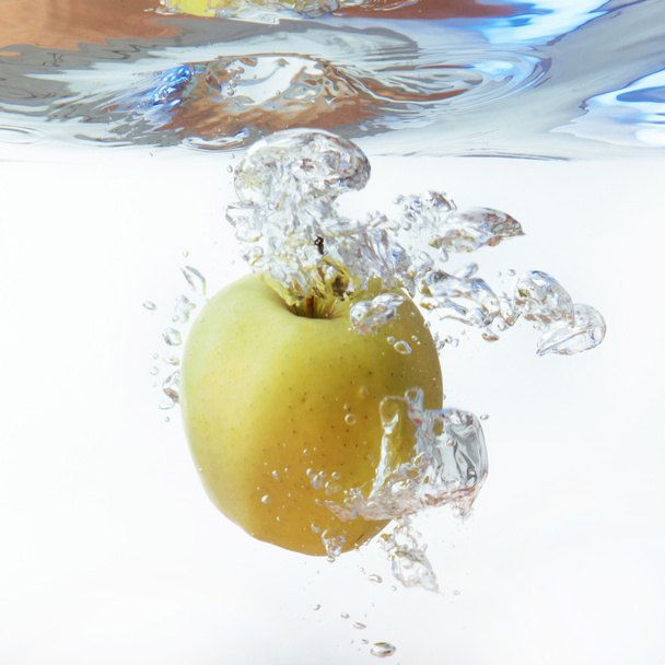 Green apple under water with a trail of transparent bubbles. - Φωτογραφία, εικόνα