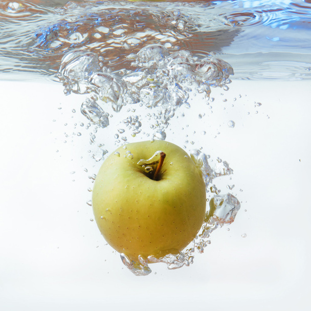 Green apple under water with a trail of transparent bubbles. - Zdjęcie, obraz