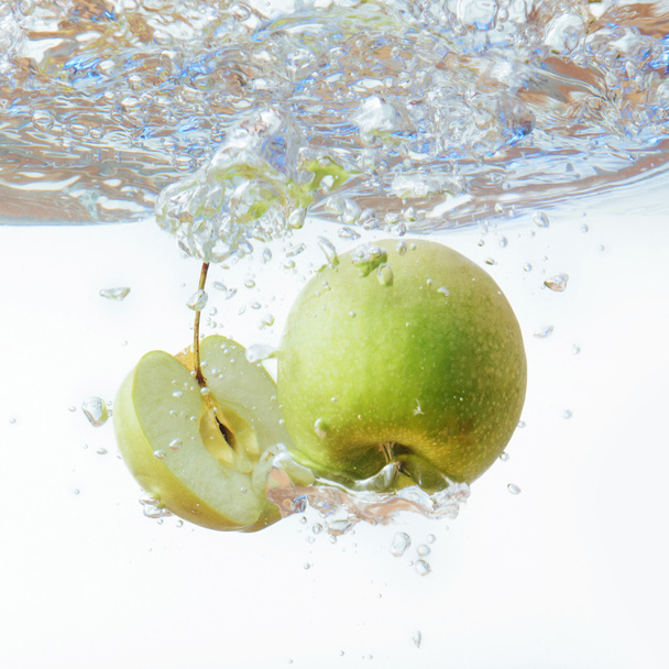 Green apple under water with a trail of transparent bubbles. - Photo, Image