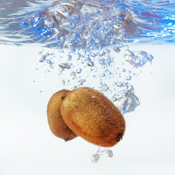 Bubbles forming in blue water after kiwi is dropped into it. - Fotografie, Obrázek