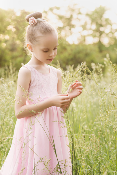 szép kislány egy fehér ruhában pózol a fűben  - Fotó, kép