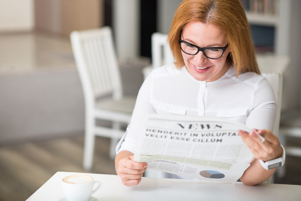Joyful woman reading newspaper - Фото, зображення