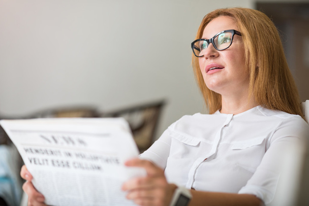 Pleasant thoughtful woman reading newspaper - Photo, image