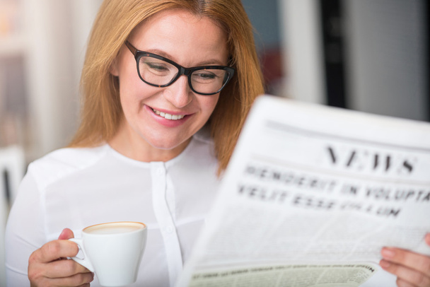 Cheerful woman reading newspaper. - Valokuva, kuva