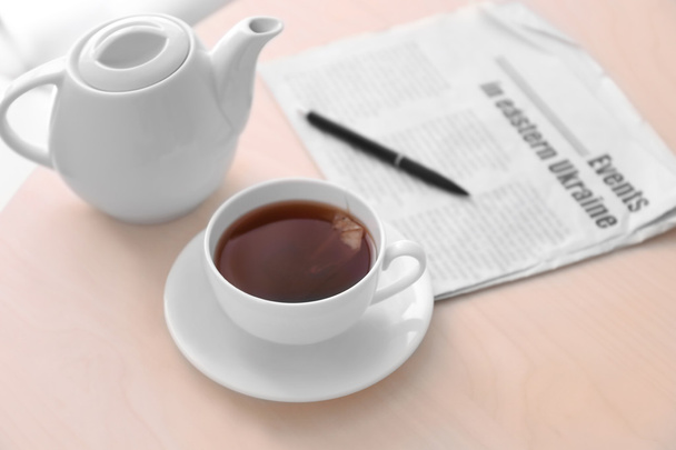 Cup of tea with newspaper on table - Φωτογραφία, εικόνα