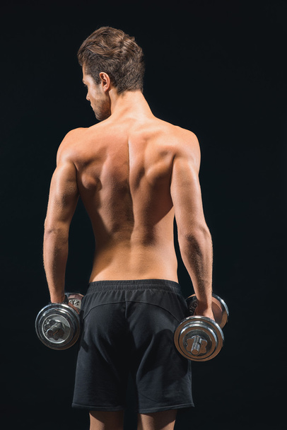 Attractive young man training with dumbbells - Foto, imagen