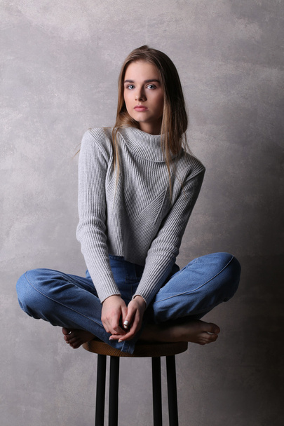 Girl on a bar chair with crossed legs. Gray background - Fotó, kép