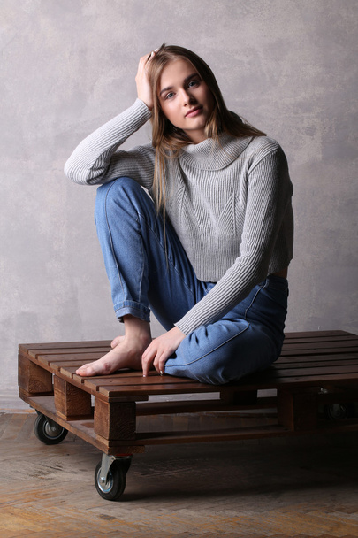 Girl in sweater holding her head. Gray background - Zdjęcie, obraz