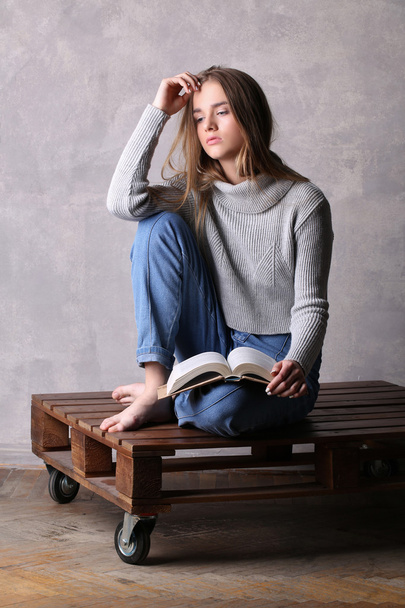 Sitting model holding a book. Gray background - Valokuva, kuva