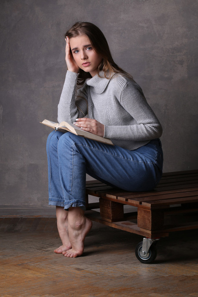 Sitting model with a book. Gray background - Фото, изображение