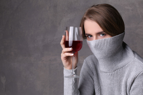 Girl with wine hiding her face by collar. Close up. Gray background - Fotoğraf, Görsel