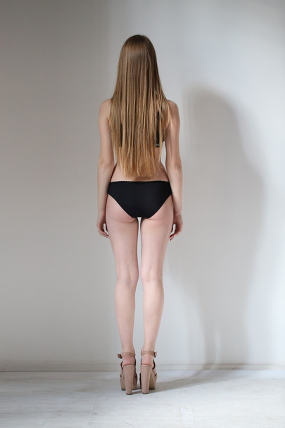 Naked girl standing back. White background - Foto, afbeelding
